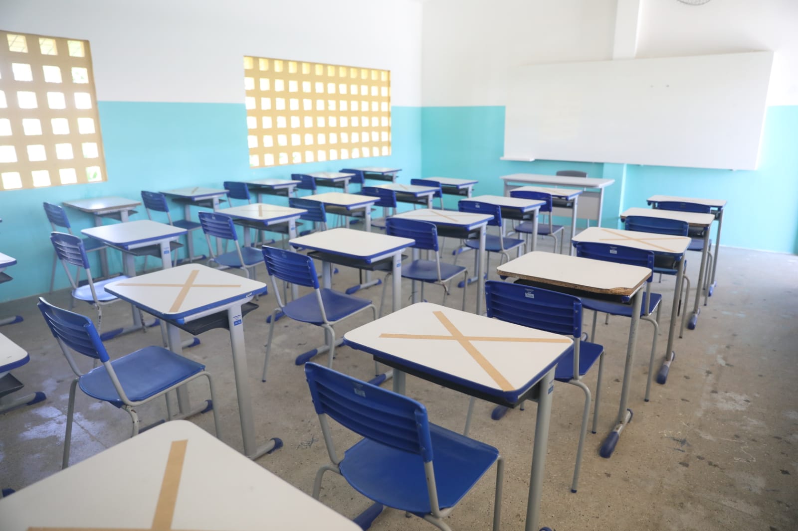 a foto mostra uma sala de aula vazia, as carteiras são marcadas com x para que haja alternância onde os alunos vão sentar